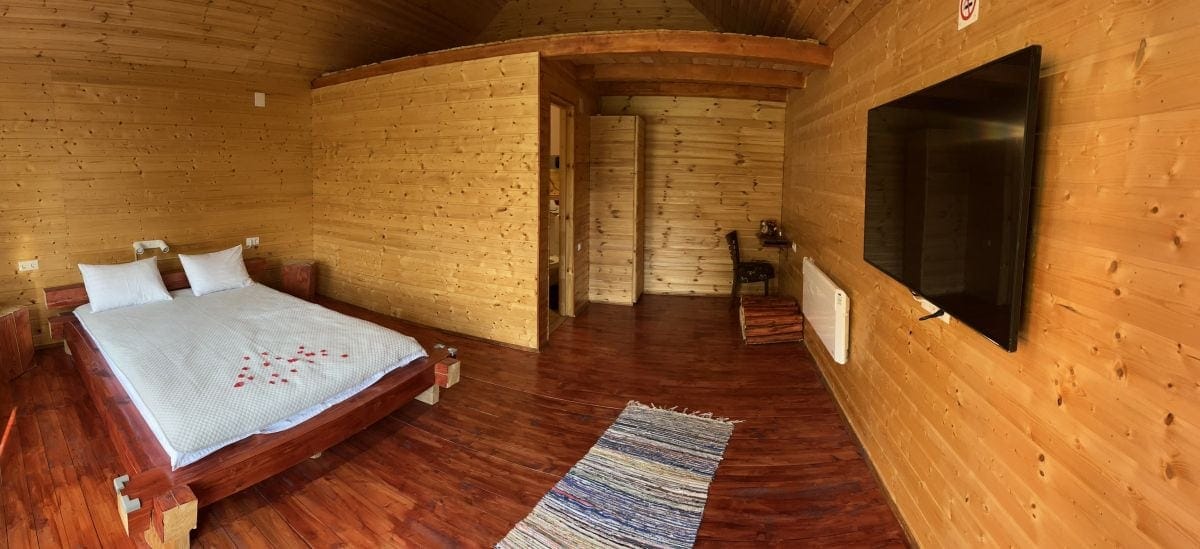 Interiorul din lemn al cabanei, cu pat dublu și televizor